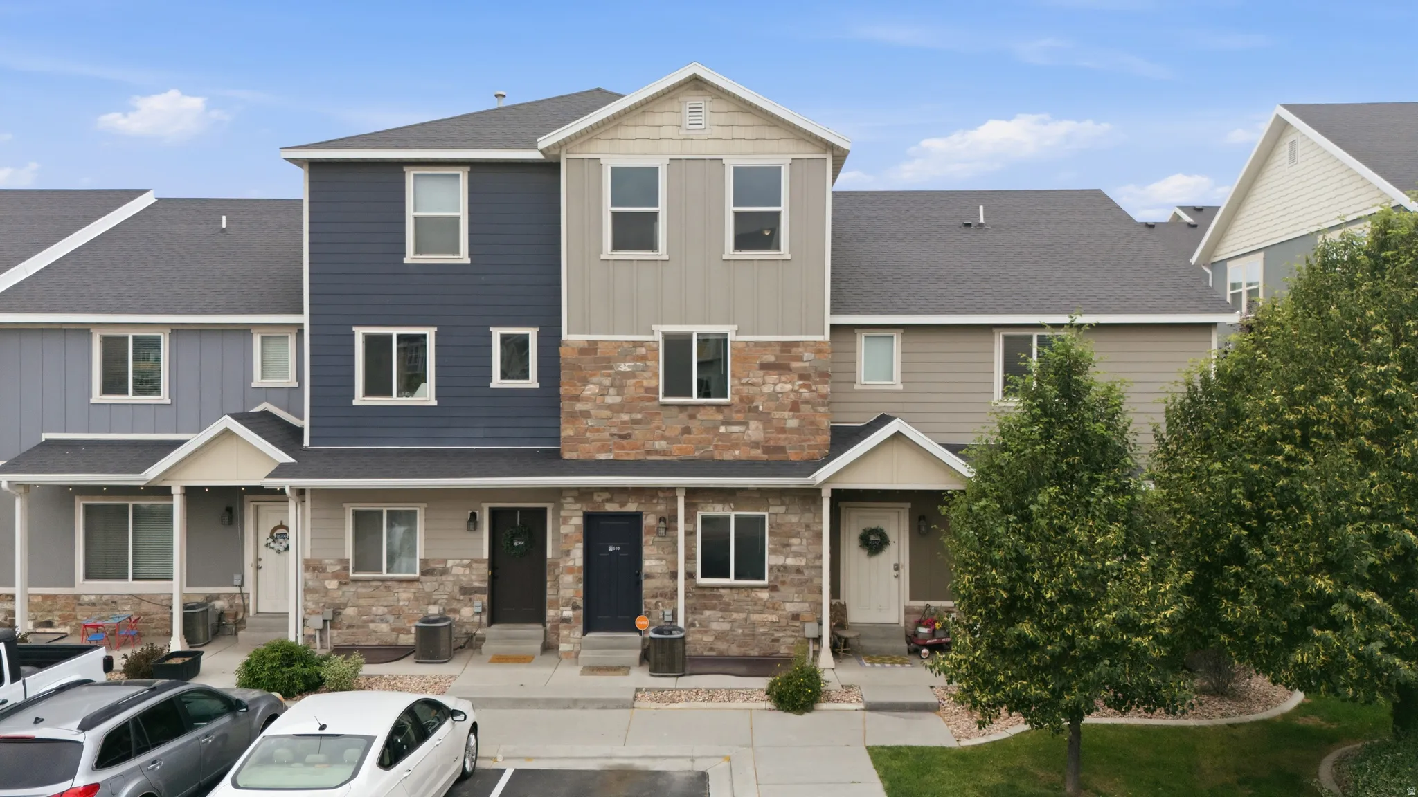 Multi-level townhome featuring a stone and siding exterior with a pitched roof