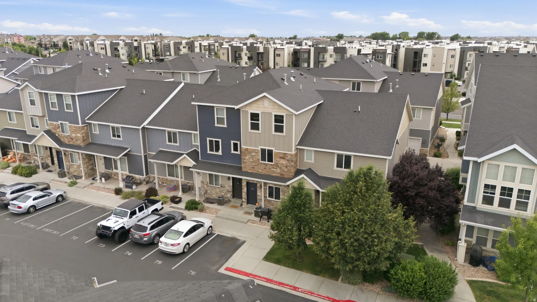 Townhome community featuring multi-story residences with varied siding, stone accents, and dark pitched roofs