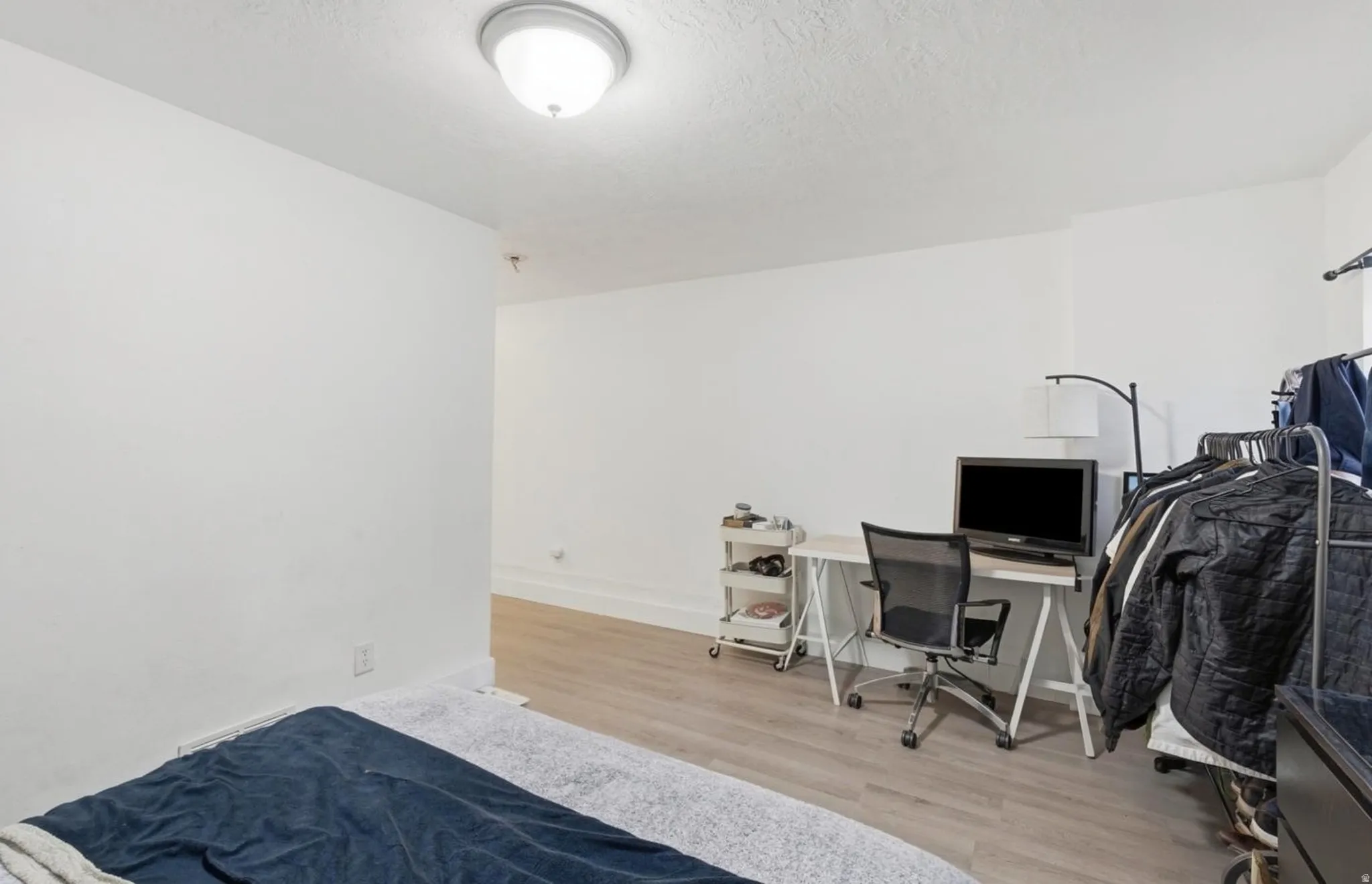 Spacious room featuring light wood-finish flooring and crisp white walls