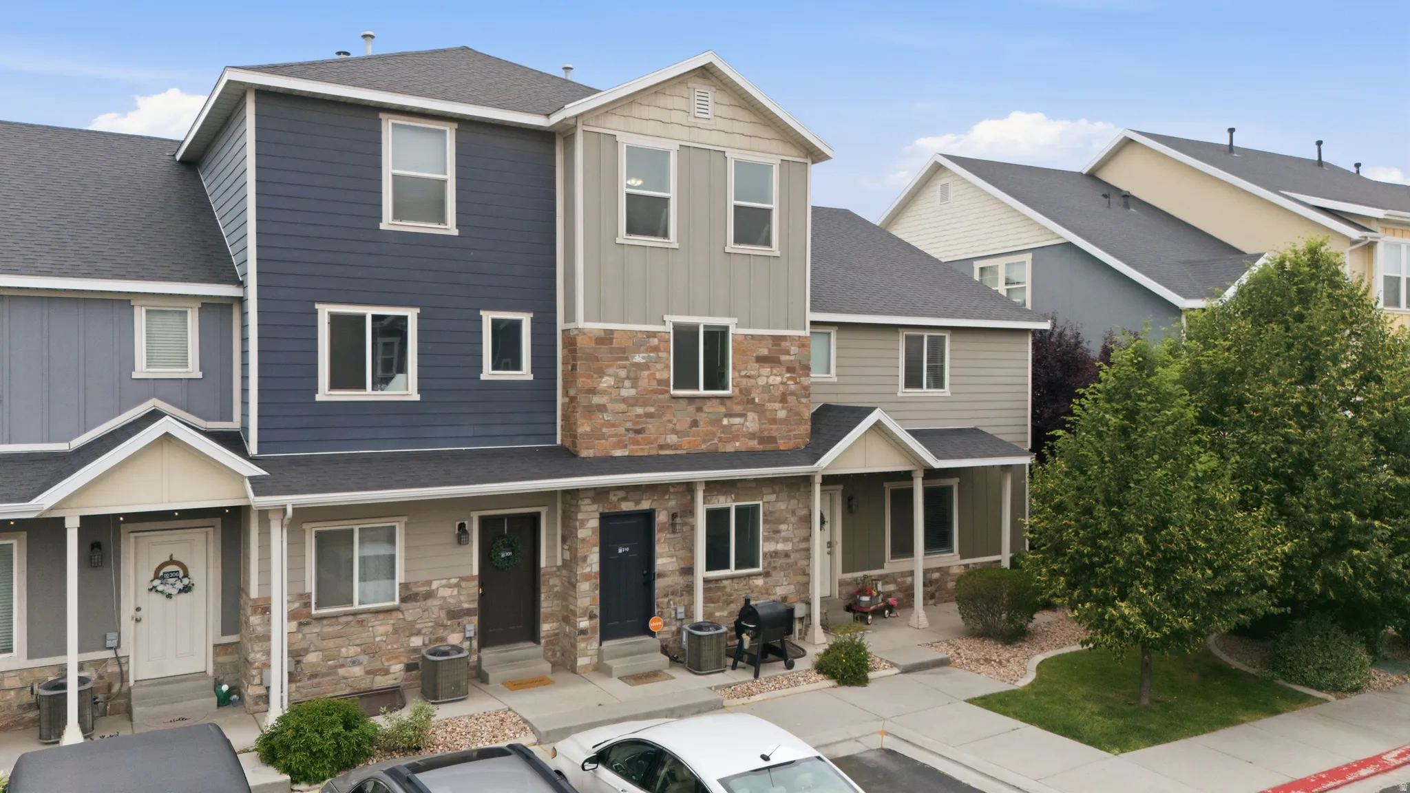 Multi-level townhome featuring a stone and siding exterior