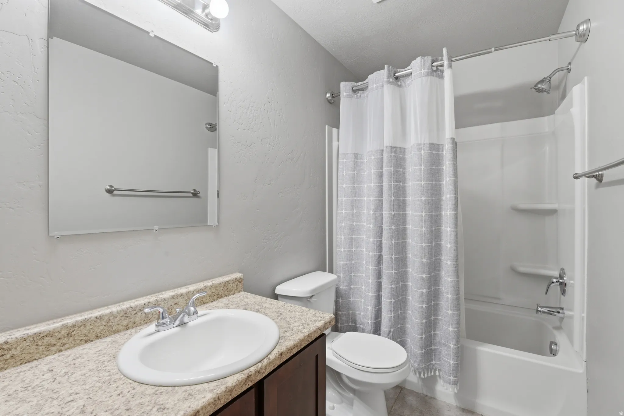 Bathroom featuring a white bathtub and shower combination, a toilet, and a vanity with a light-colored countertop