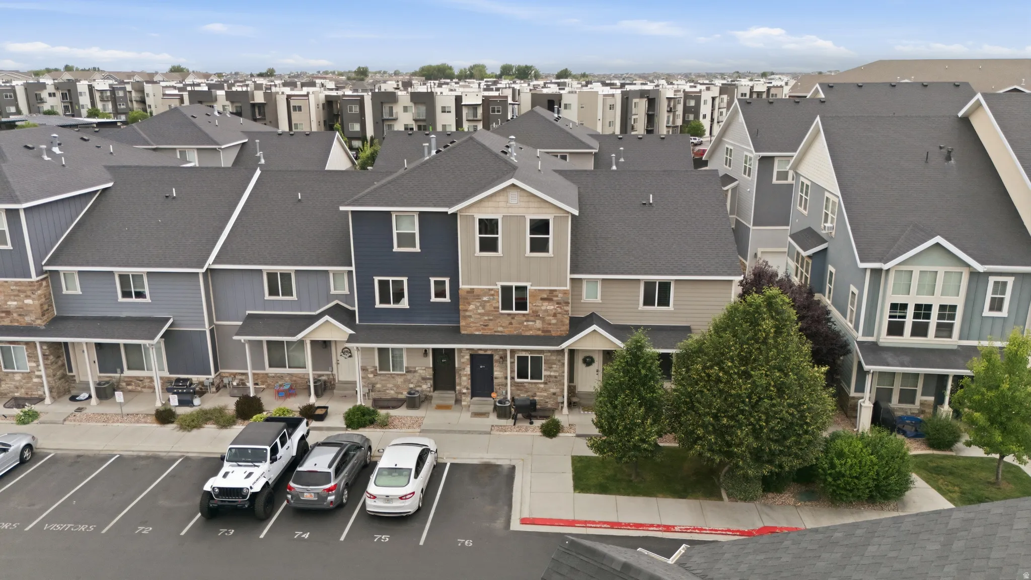 Modern townhome exterior featuring multi-toned siding, stone accents, and dark pitched roofs