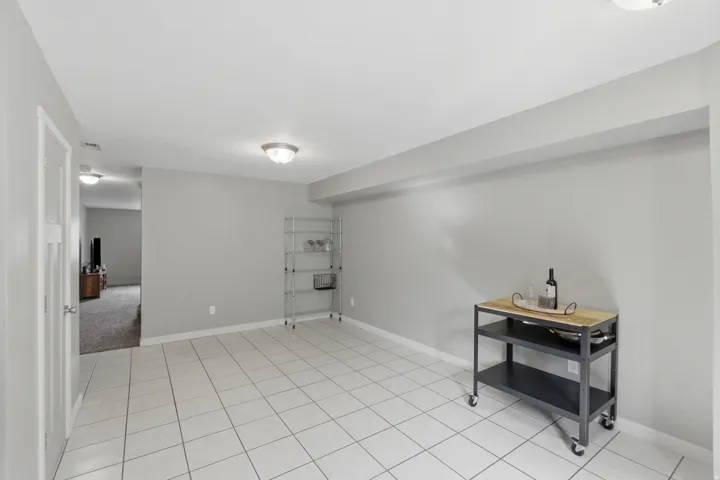 Spacious room featuring light-toned tile flooring, neutral wall paint, and ceiling-mounted lighting fixtures