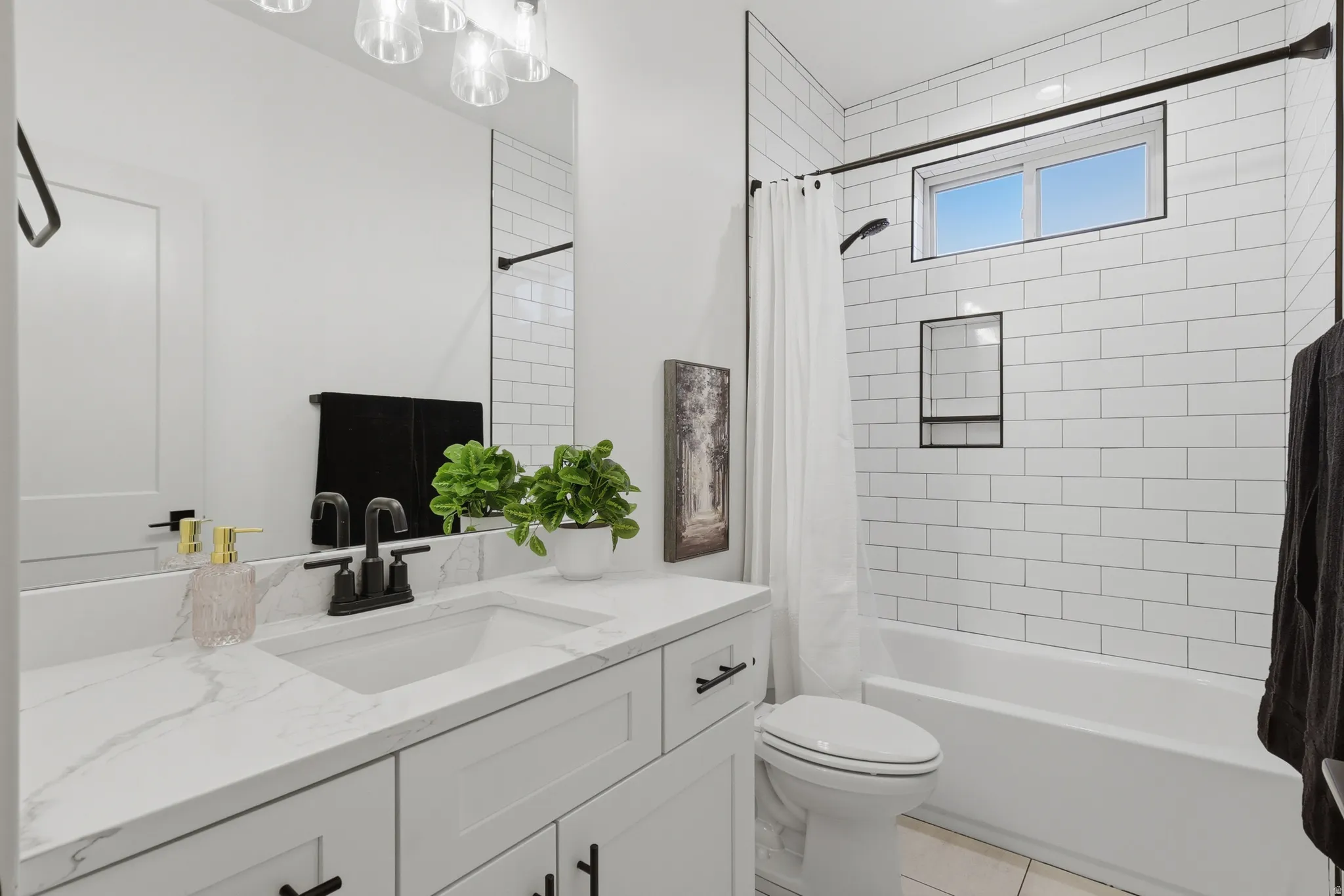 Modern bathroom featuring a single vanity with a white countertop and undermount sink, black-finish faucet, and a large mirror