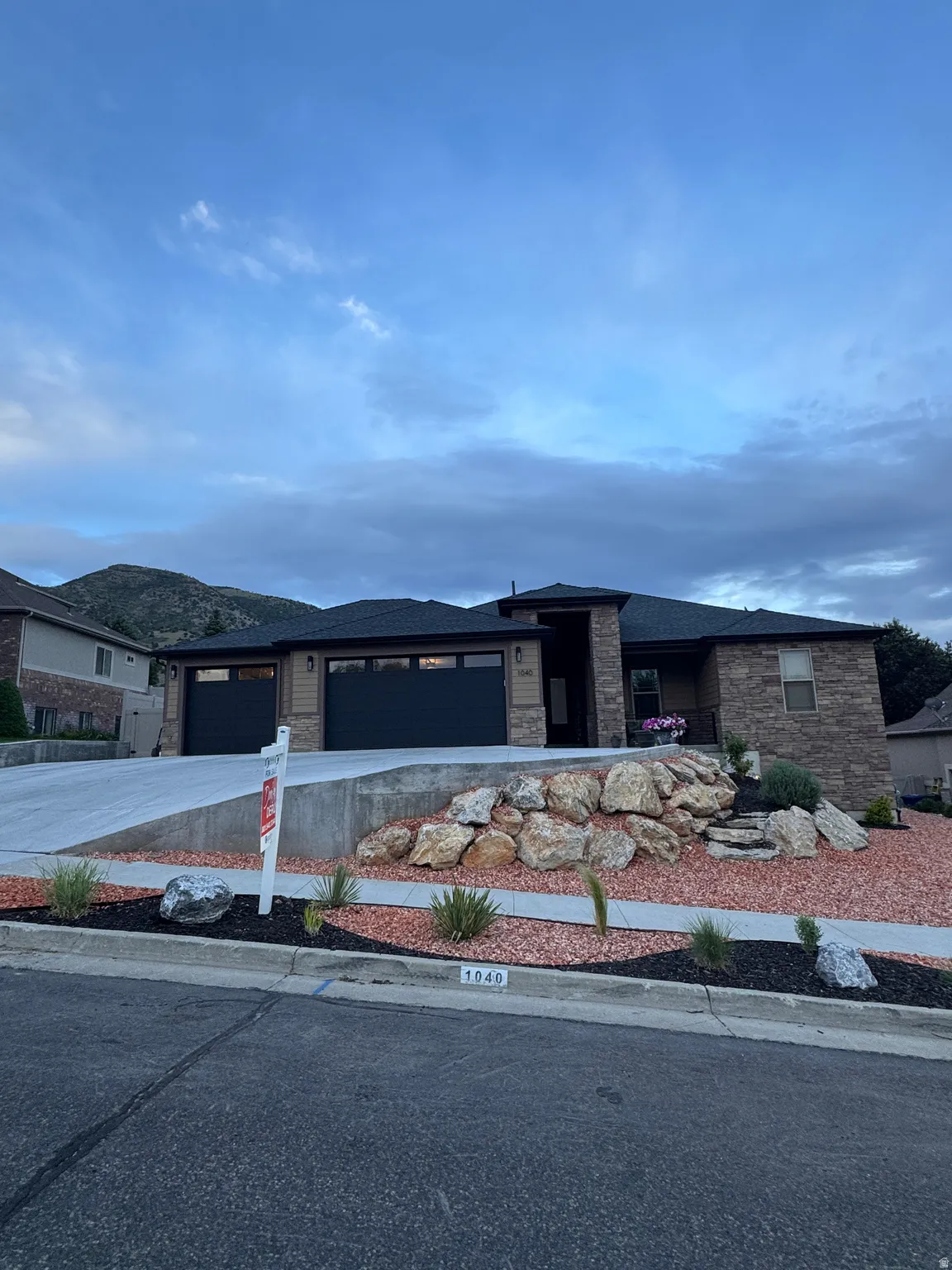 Contemporary ranch-style residence featuring stone and horizontal siding accents, a paved driveway, and a two-car garage