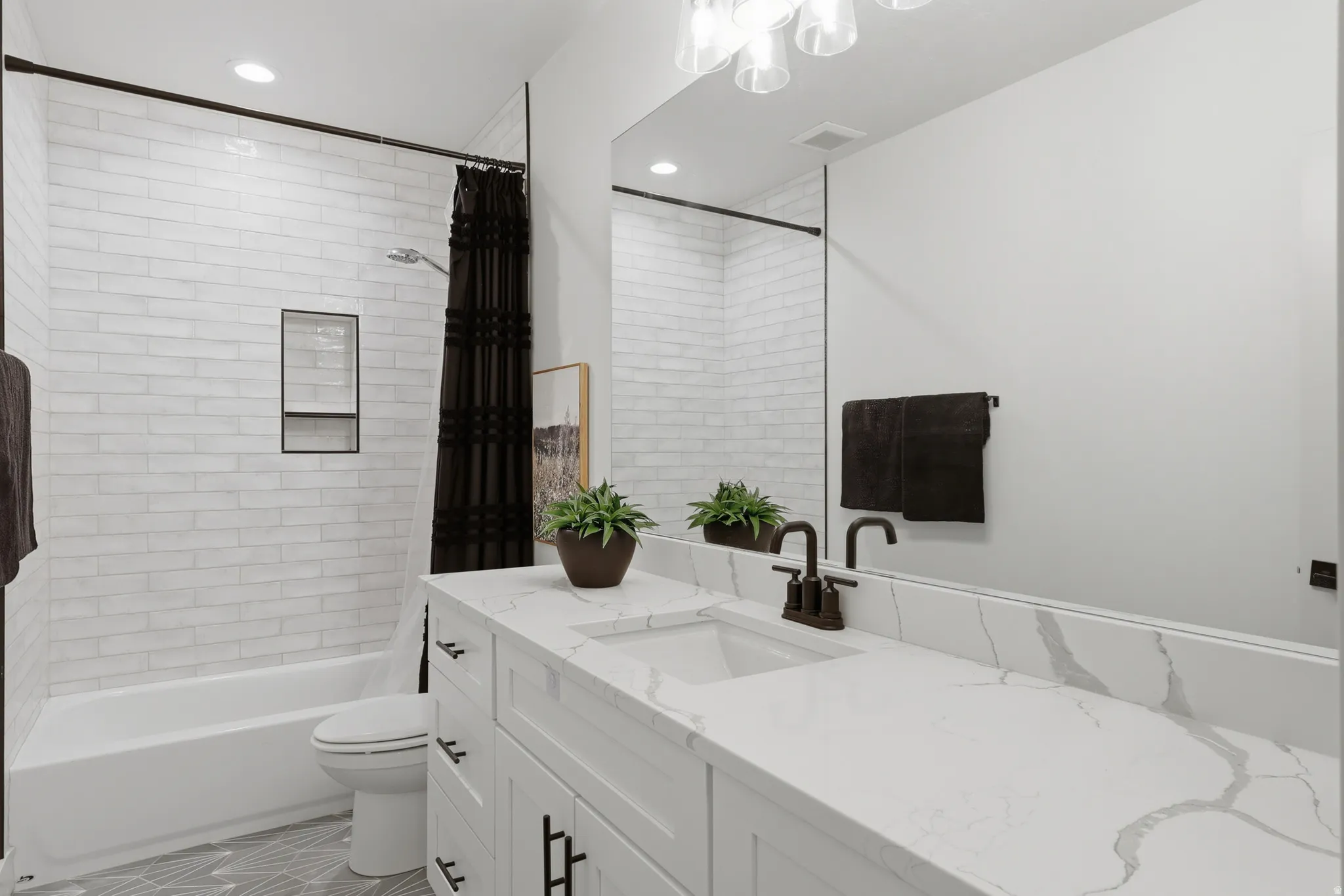 Bathroom featuring a white subway tile shower surround with a built-in niche, a white tub, and a vanity with a white countertop