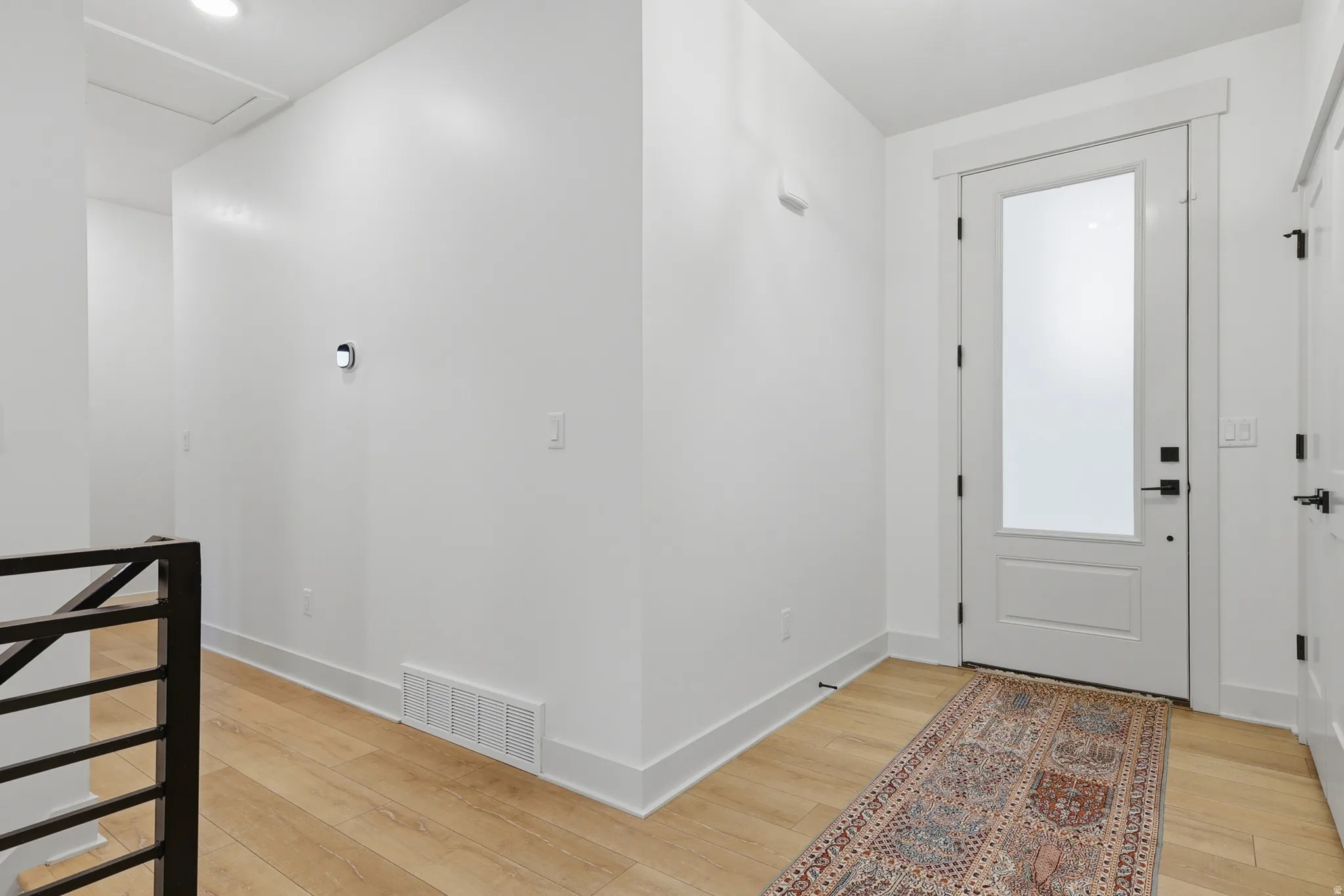 Entryway featuring a white door with frosted glass panel and black hardware