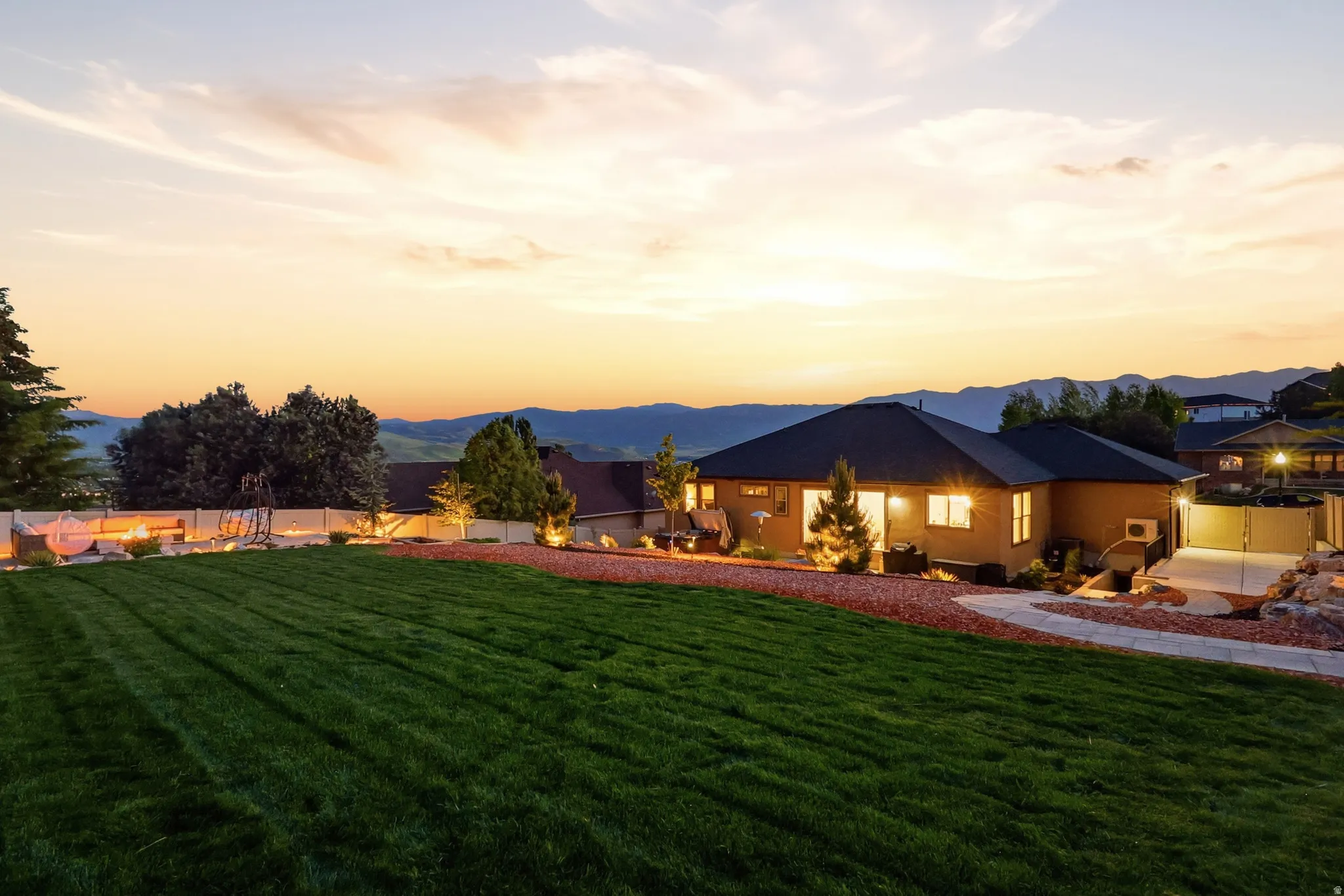 Expansive backyard featuring a manicured lawn, a concrete pathway, and a gravel-bordered landscape with mature trees