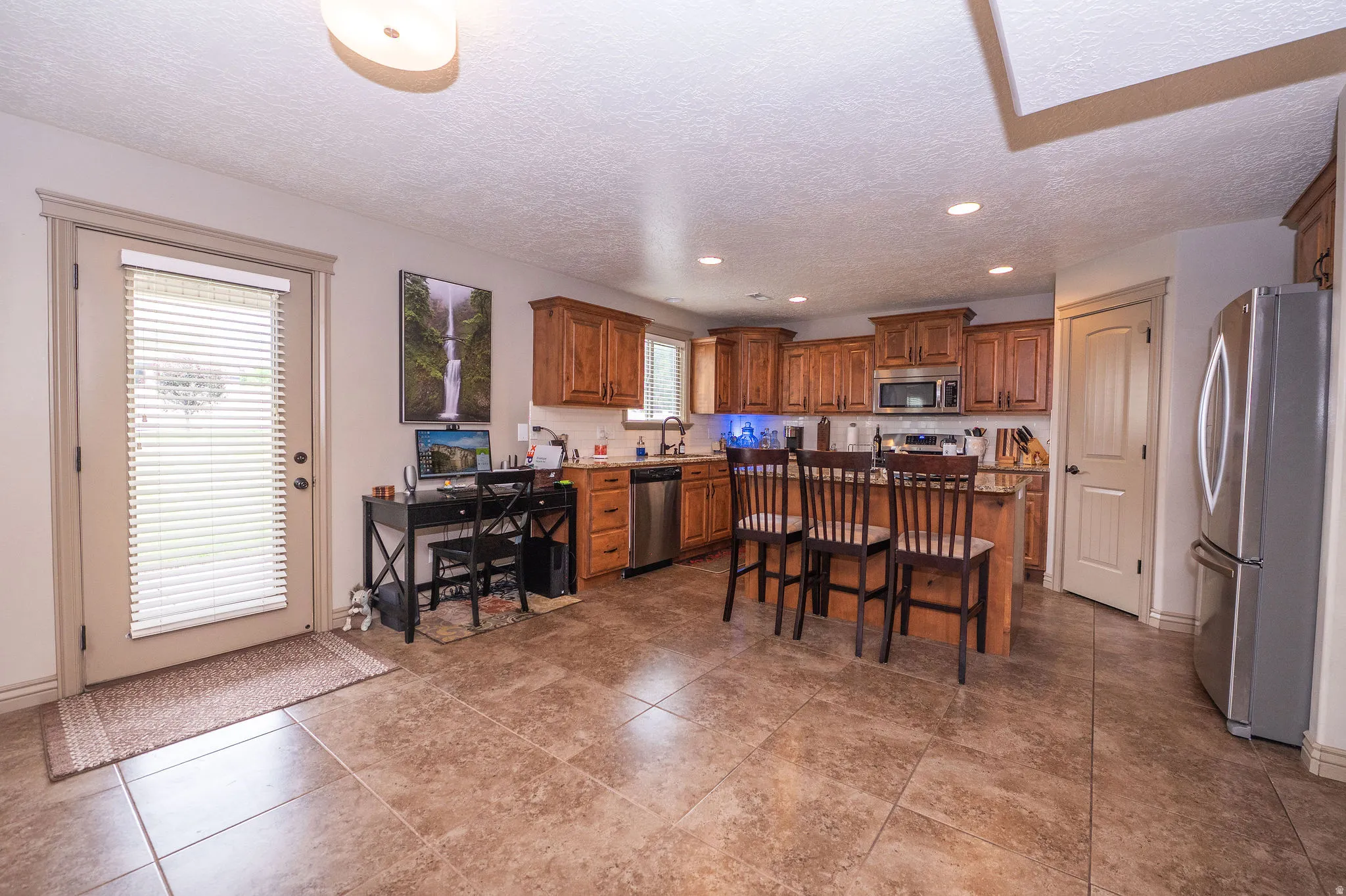 Kitchen featuring wood cabinetry, stainless steel appliances, and a central island with bar seating