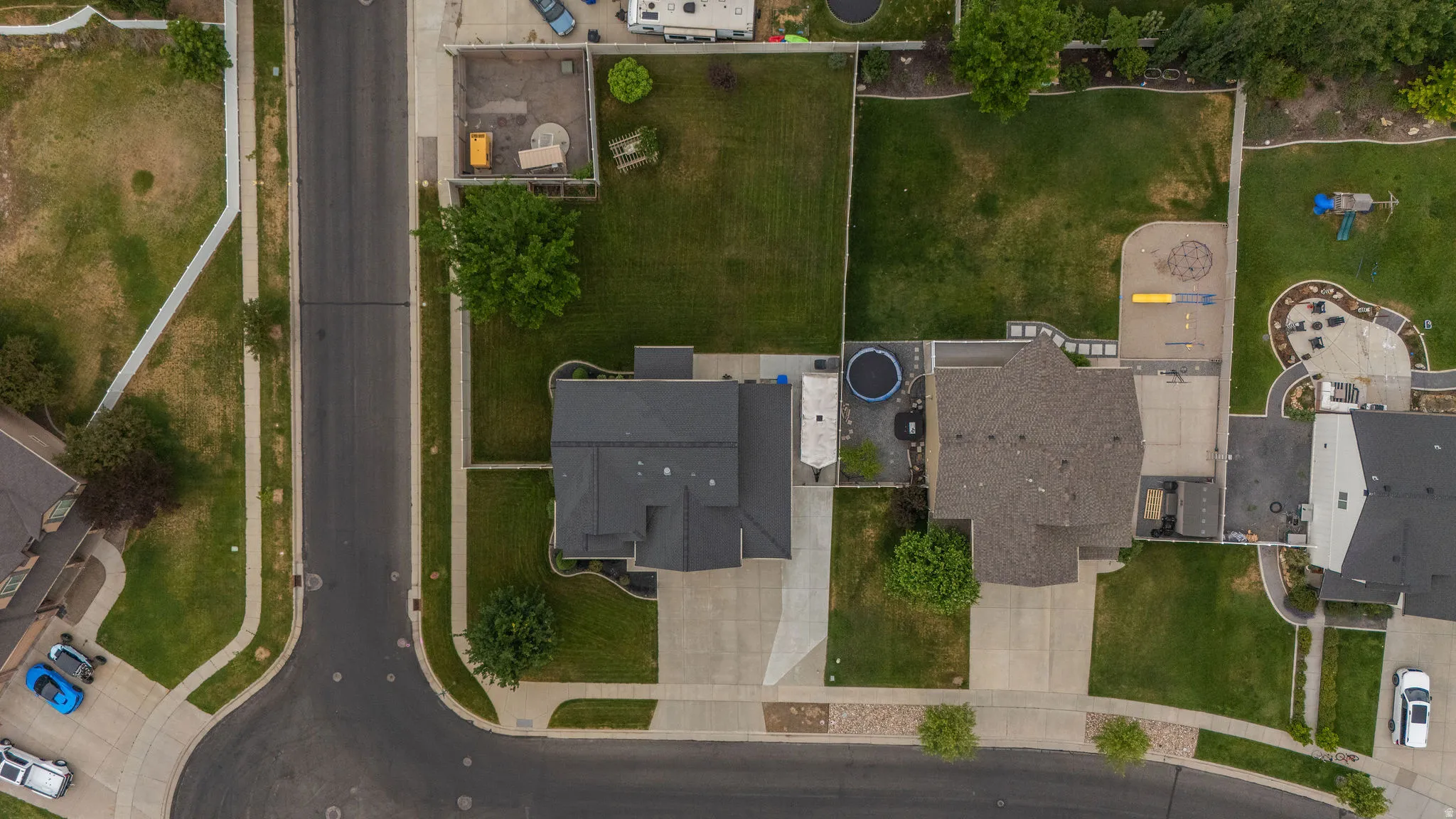 Property featuring a dark shingle roof, expansive front lawn, paved driveway, and established landscaping