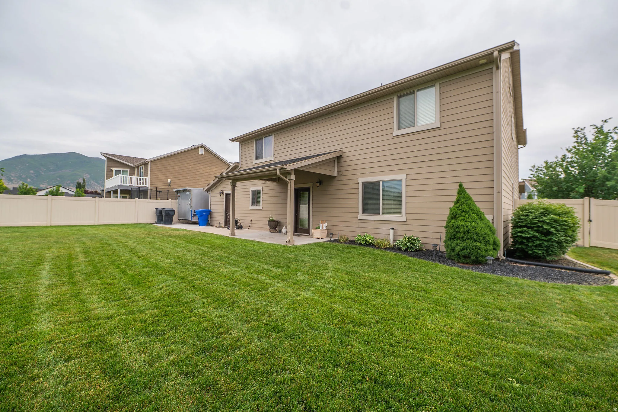 Expansive lawn with a beige vinyl fence and mountain backdrop