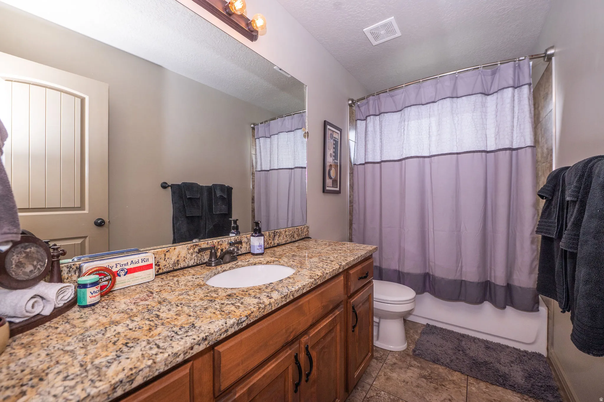 Bathroom featuring a vanity with a granite countertop, undermount sink, and wood-finish cabinetry
