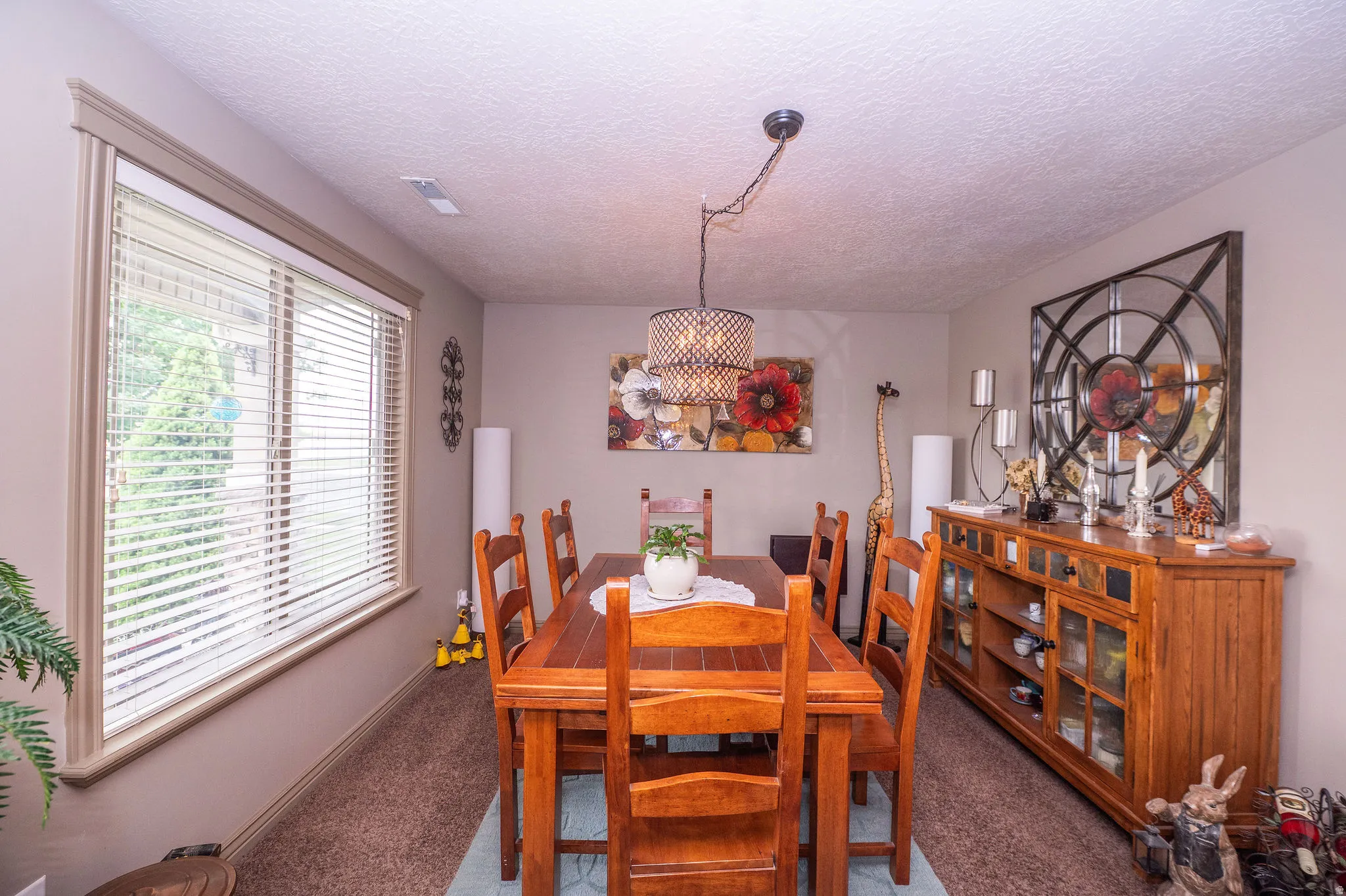 Dining area featuring a large window with blinds, a drum pendant light fixture, and neutral-toned walls