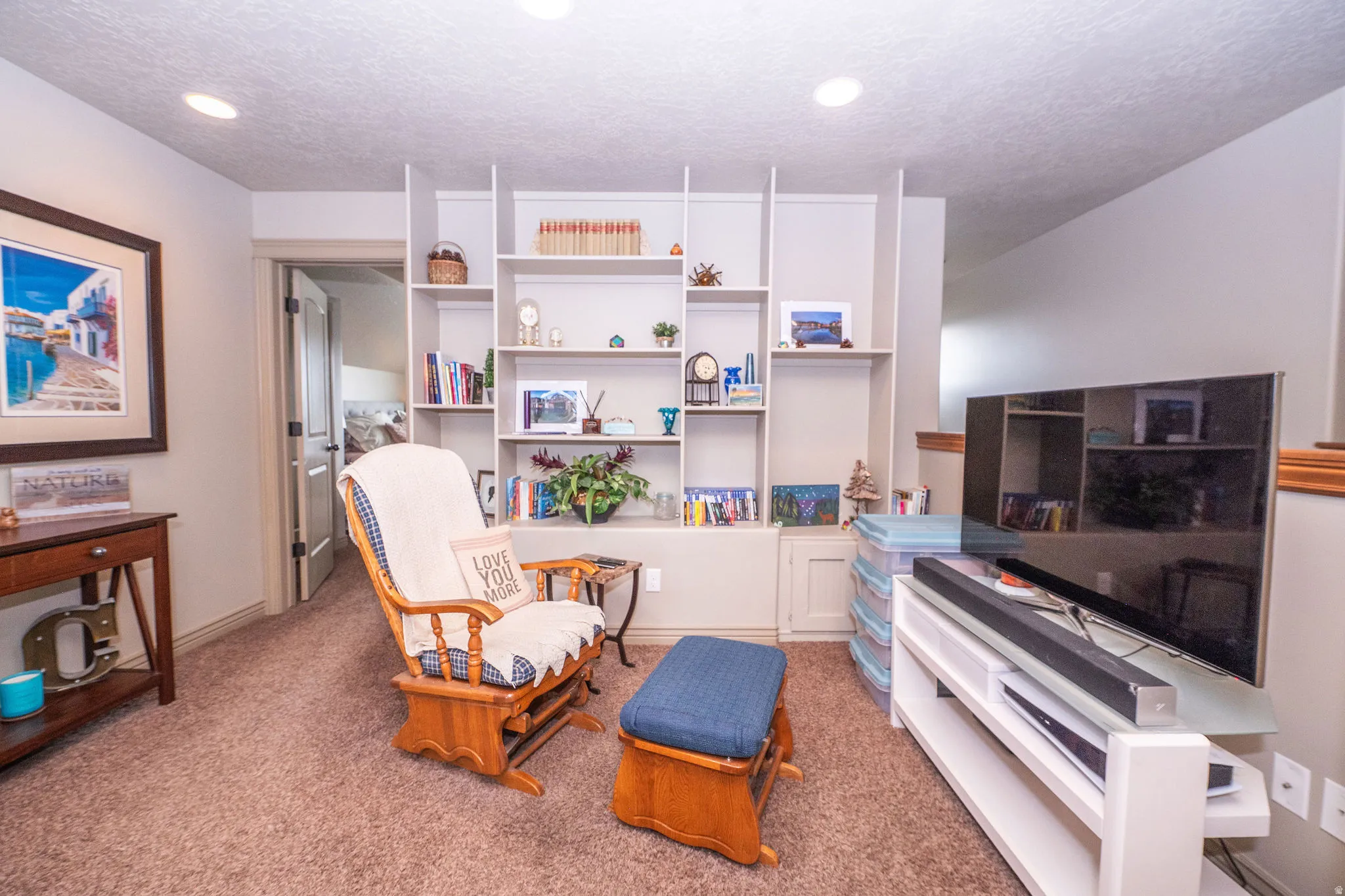 Built-in wall shelving with integrated cabinetry, recessed ceiling lighting, and neutral carpet flooring