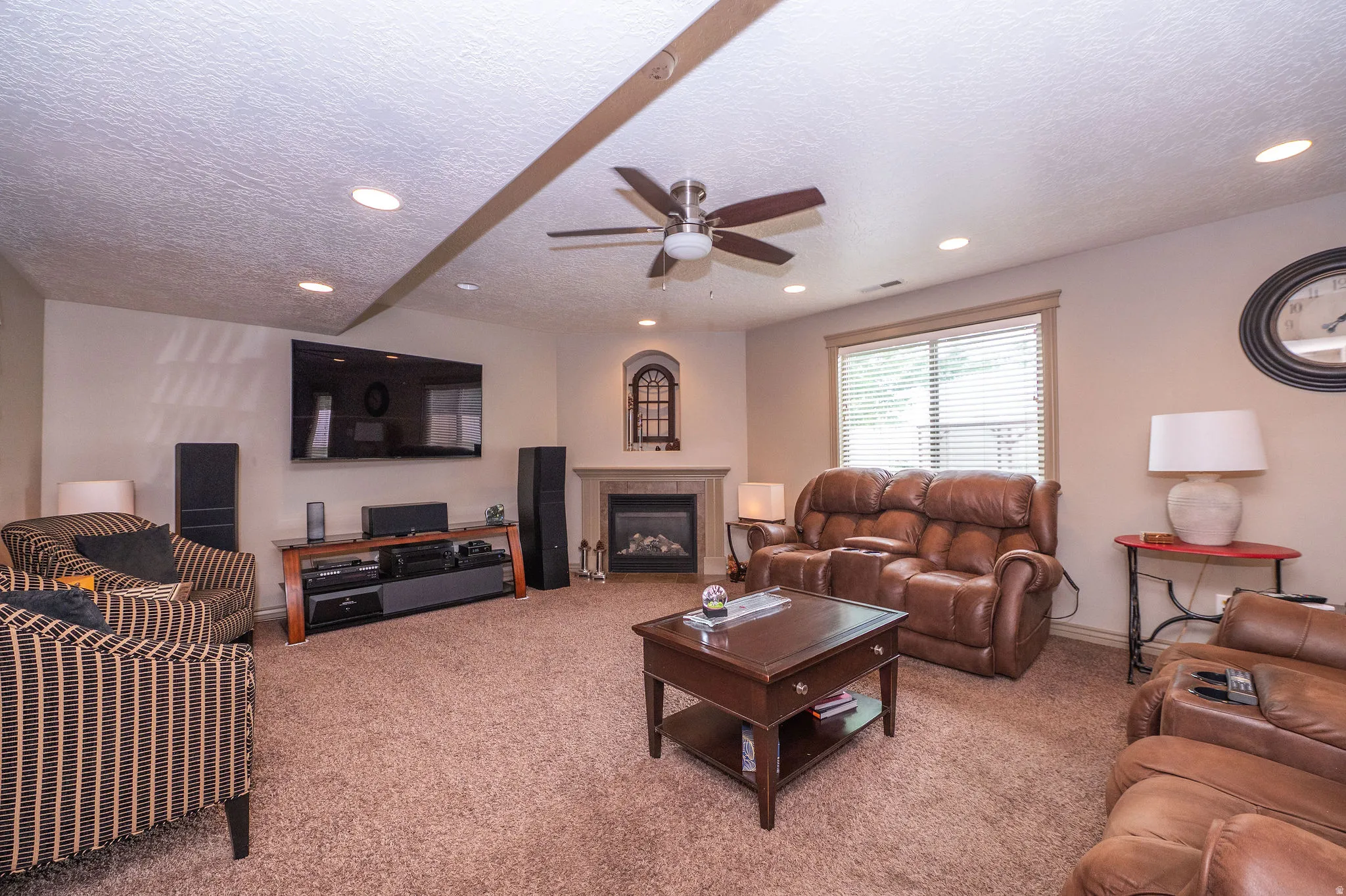 Carpeted living area featuring a built-in electric fireplace with an arched accent window, recessed lighting, and a ceiling fan