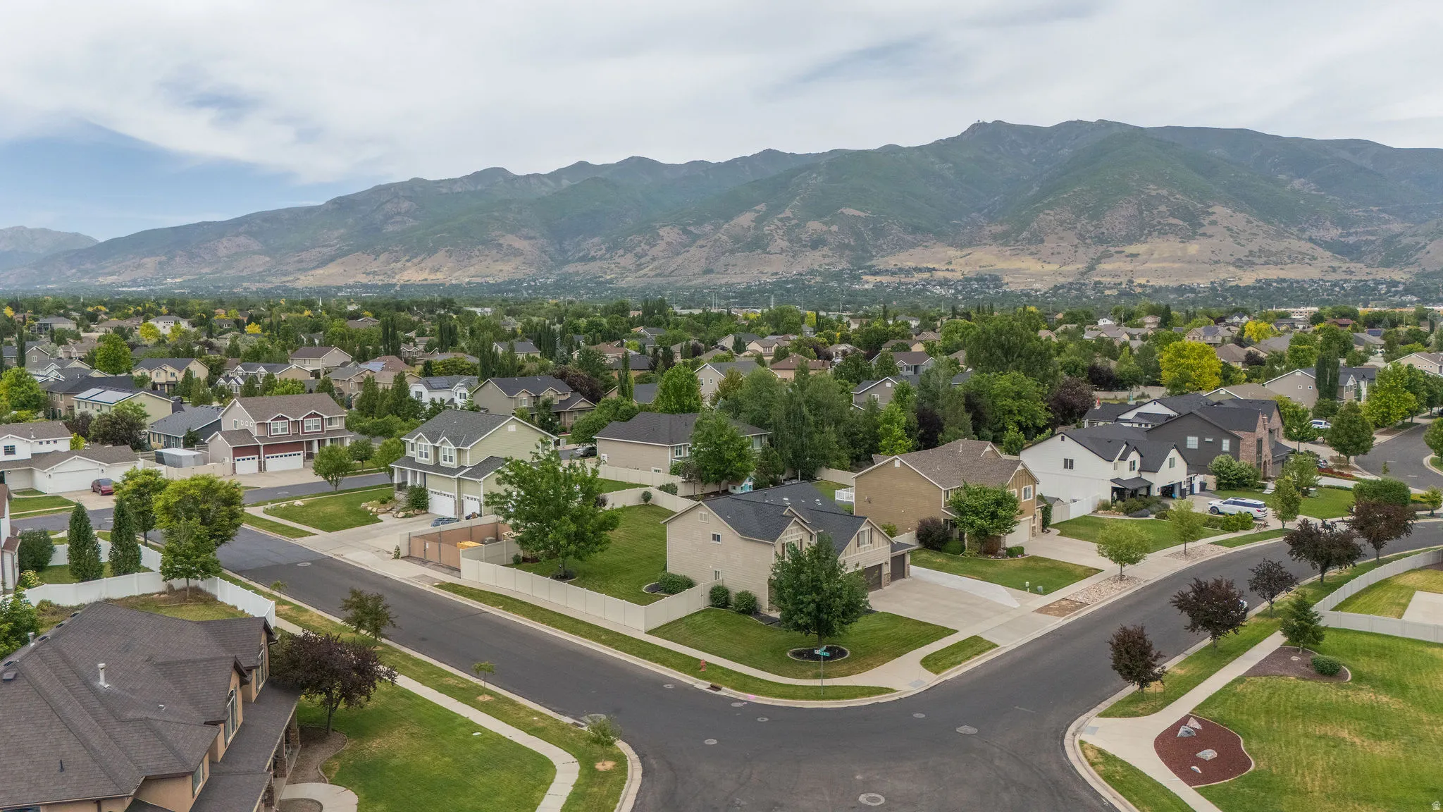 Aerial perspective showcasing a residential neighborhood with varied home designs, mature landscaping, and mountain backdrops