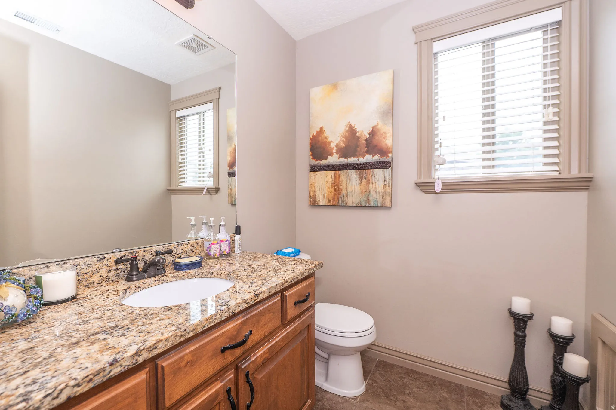 Bathroom vanity featuring a granite countertop with an undermount sink and dark bronze faucet