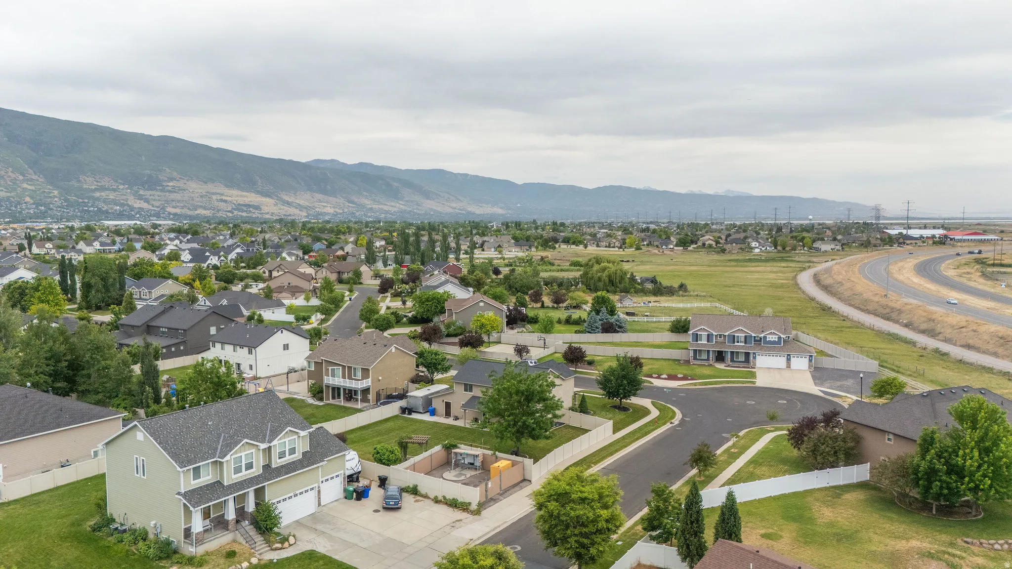 Residential area featuring a variety of single-family homes with mountain backdrops, green landscaping, and curved streets