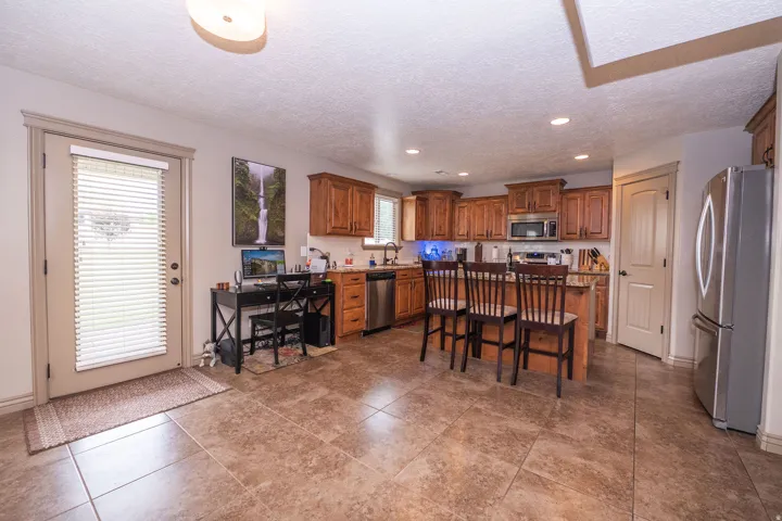 Kitchen featuring wood cabinetry, stainless steel appliances, and a central island with bar seating