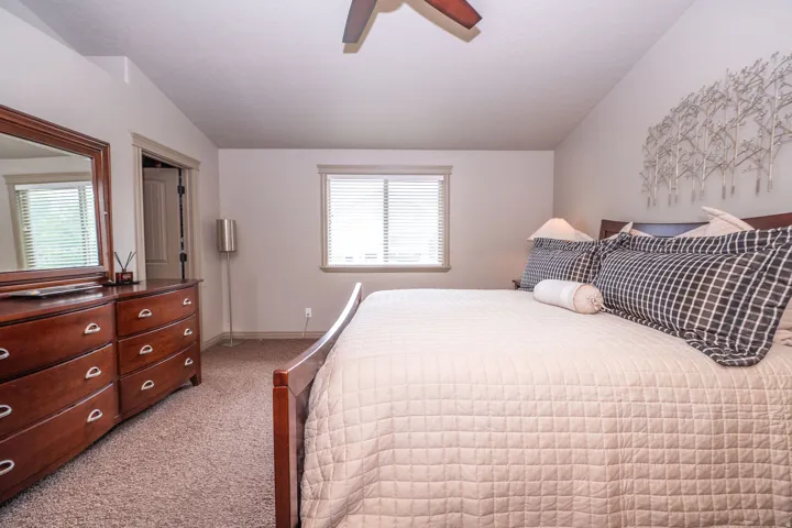 Carpeted bedroom featuring a ceiling fan, a window with blinds, and neutral wall tones