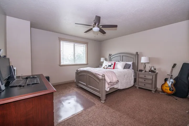 Bedroom featuring a window with blinds, a ceiling fan, and carpeted flooring