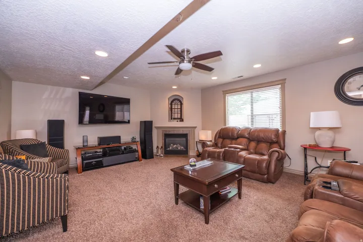 Carpeted living area featuring a built-in electric fireplace with an arched accent window, recessed lighting, and a ceiling fan