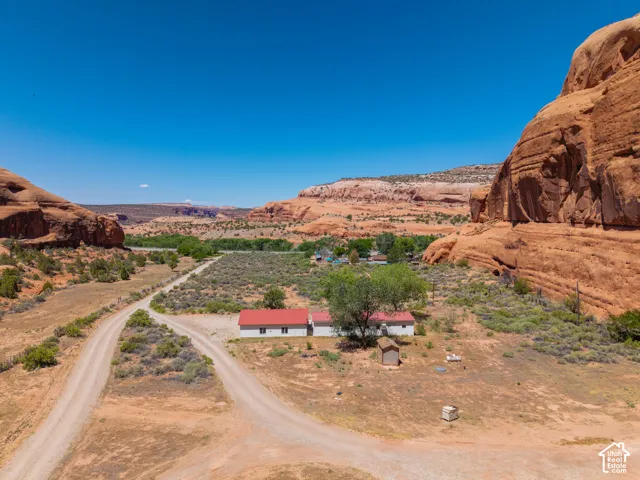 Rural property featuring a white residence with red roofing, surrounded by expansive desert landscaping