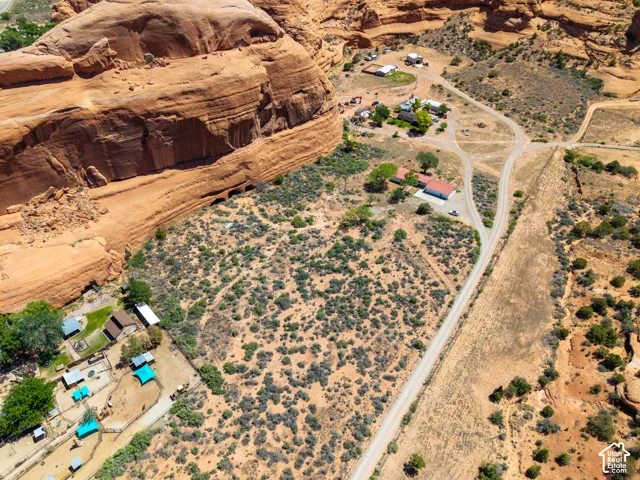 Expansive property nestled against a natural rock formation, featuring multiple buildings, unpaved roadways, and native vegetation