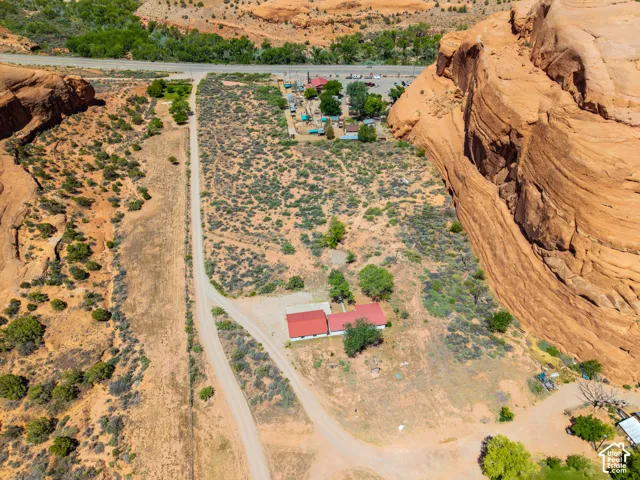 Sprawling desert property featuring a single-story residence with a red roof, a separate outbuilding, and natural rock formations