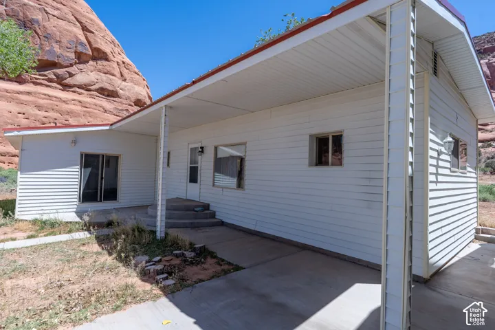 White vinyl siding exterior with an attached covered porch and concrete patio
