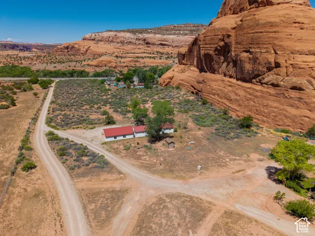 Expansive desert property featuring a white-sided building with a red roof, multiple dirt access roads, and natural rock formations
