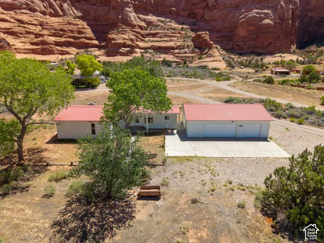 Property featuring a detached garage with an expansive concrete pad, a white exterior, and a red metal roof