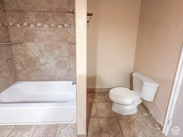 Full bathtub with a chrome shower head and tiled surround