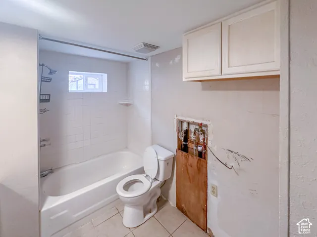 White tiled shower surround with a built-in tub, a window, and a wall-mounted showerhead