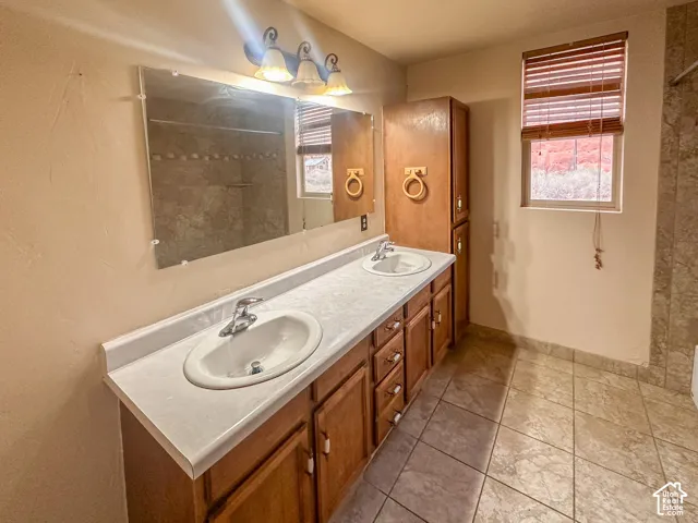 Dual vanity with light-toned countertop, wood-finish cabinetry, and integrated sinks