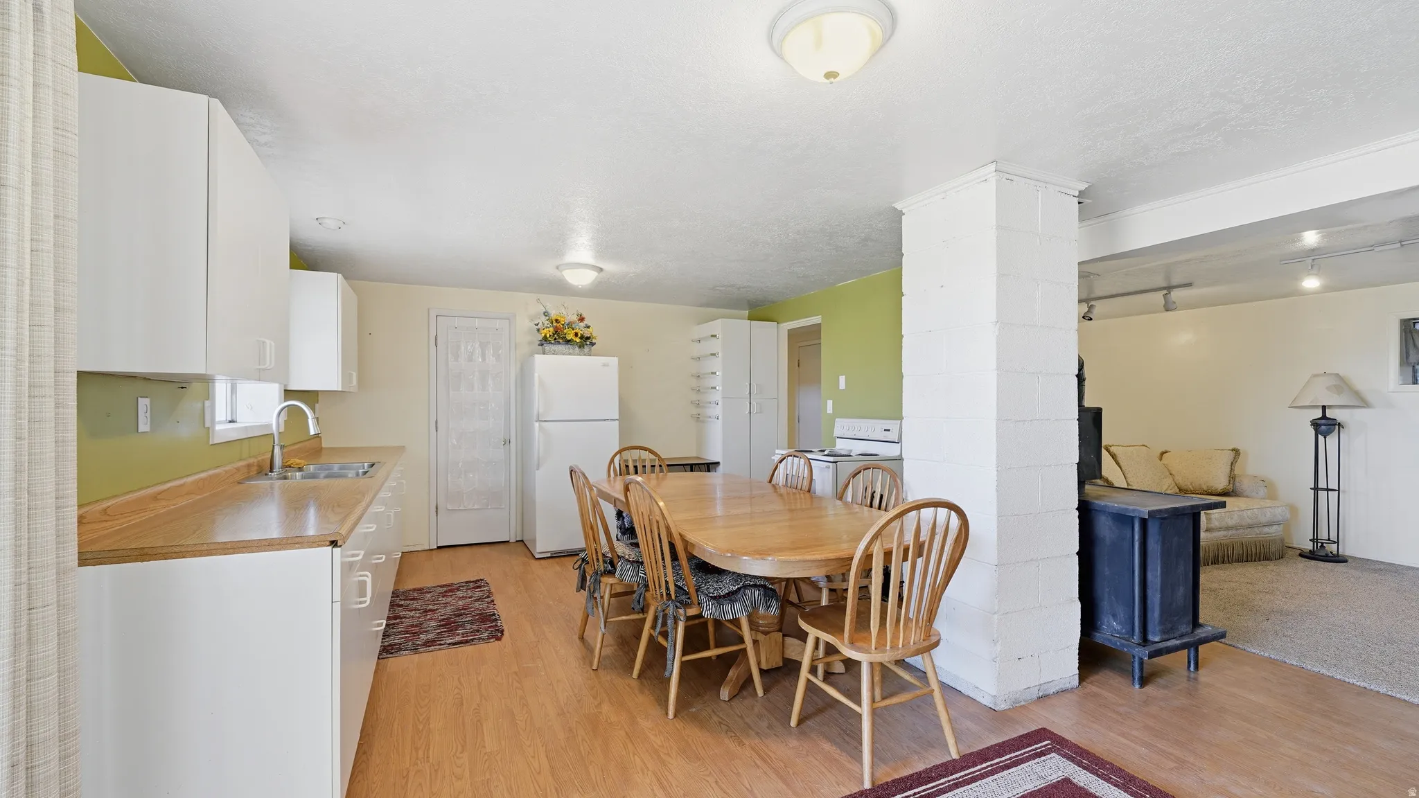 Kitchen area featuring white cabinetry, wood-finish countertops, and a stainless steel sink with a high-arch faucet