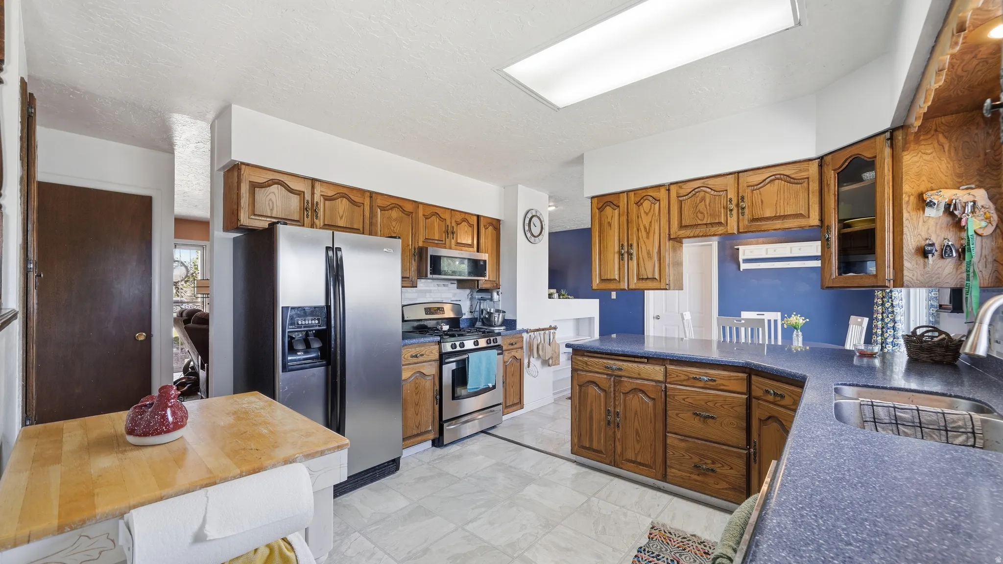 Kitchen featuring wood cabinetry, stainless steel appliances, blue countertops, and tiled flooring