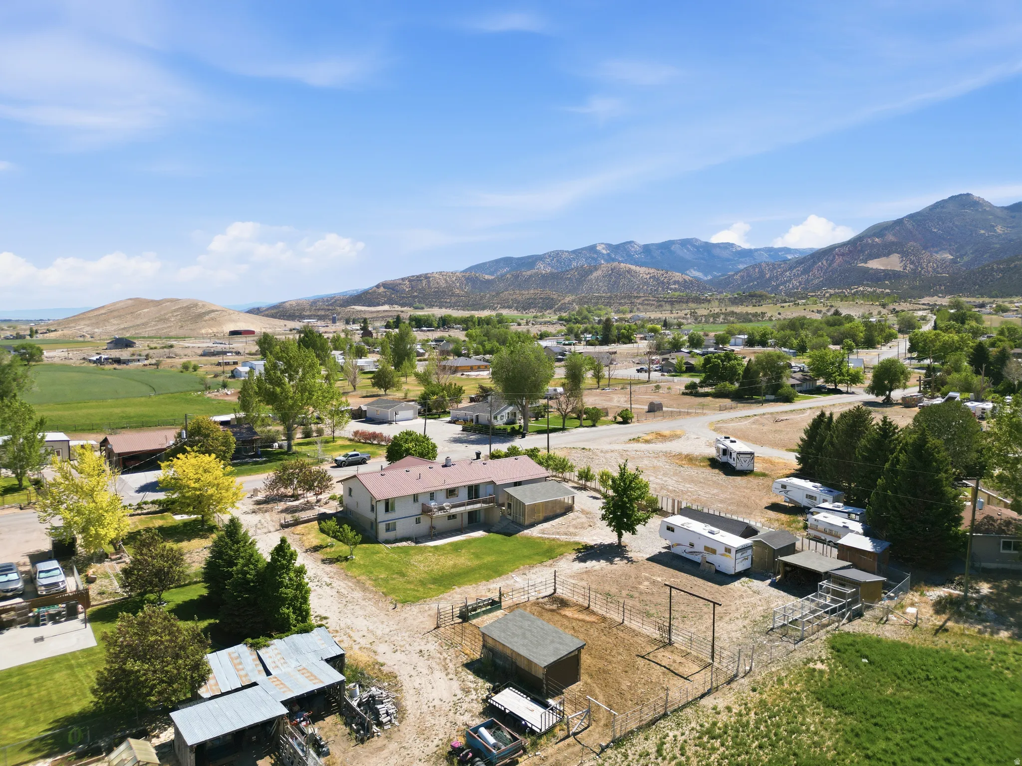 Rural property featuring mountain and valley backdrops, expansive land, several outbuildings, and mature trees