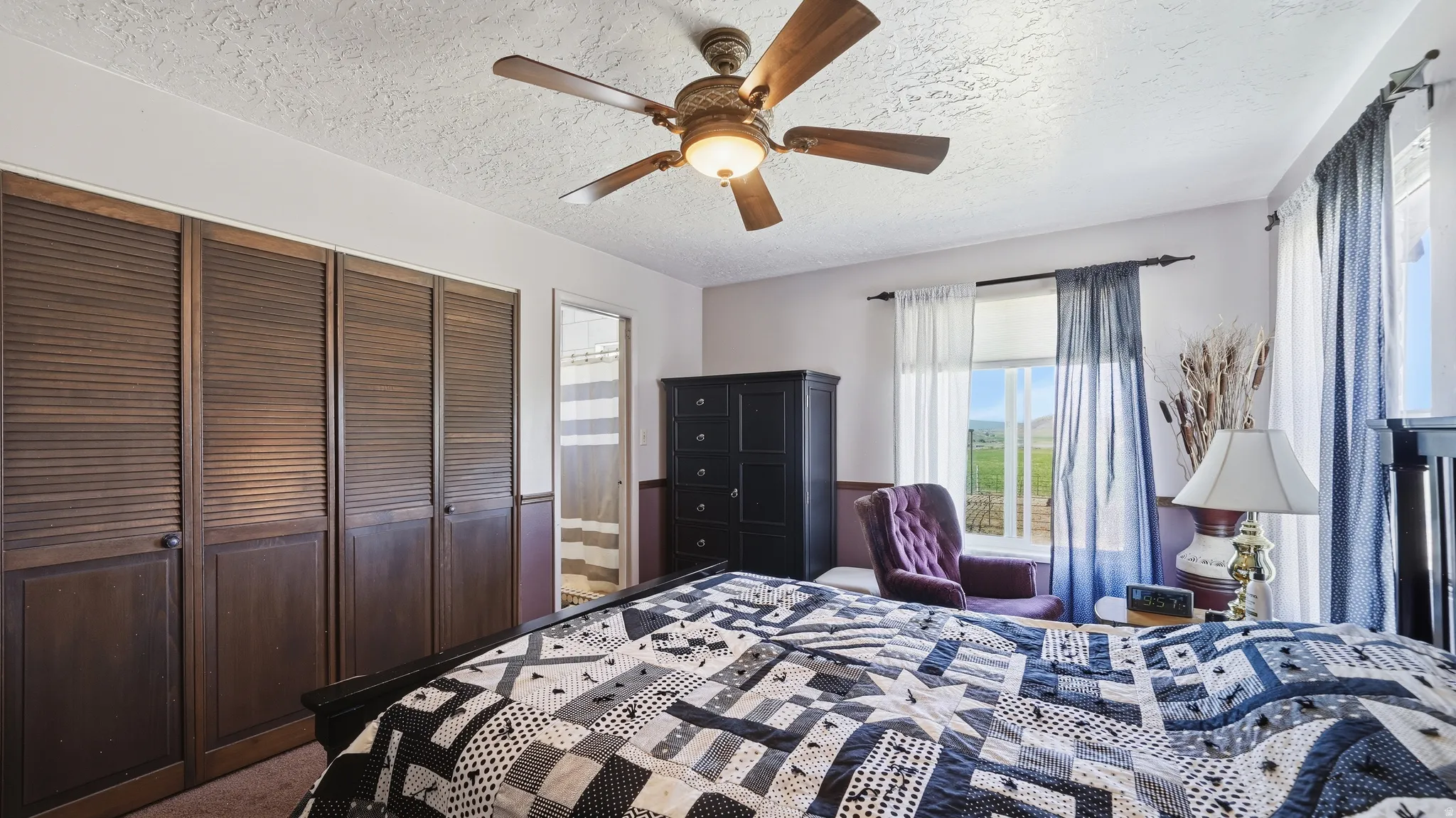 Room featuring louvered bi-fold closet doors, ceiling fan, and multiple windows with outdoor scenery