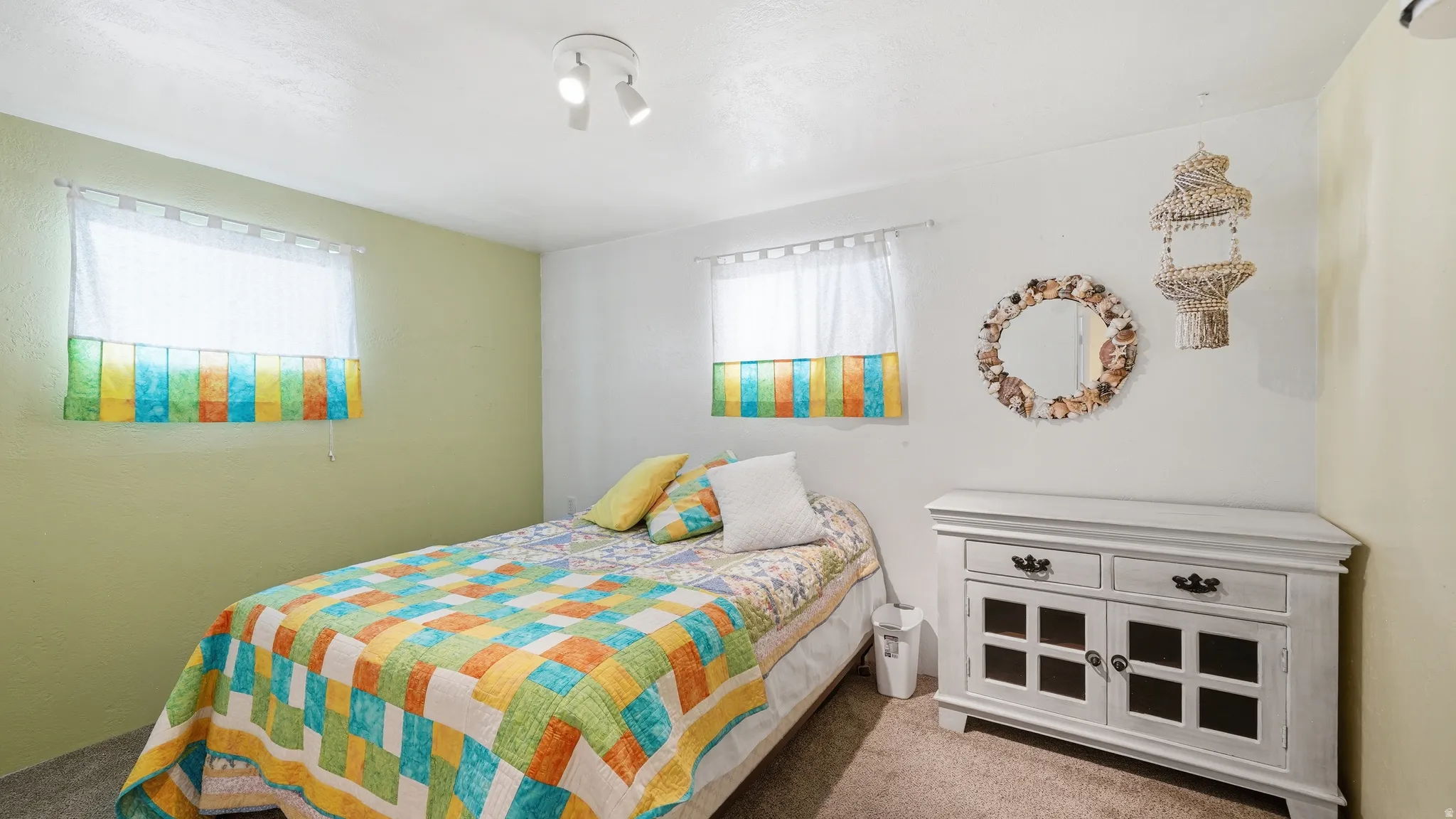 Bedroom featuring track lighting, two windows with valances, and light-colored wall finishes
