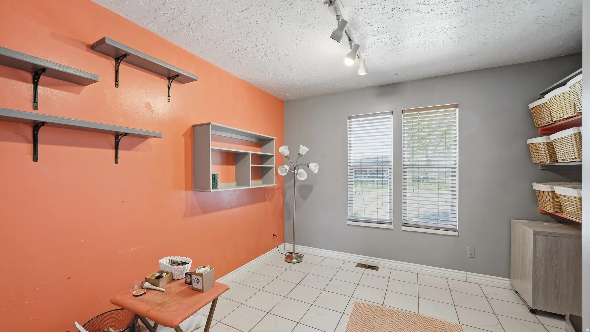Bedroom currently used as a sewing/craft room. featuring contrasting orange and grey walls with white tile flooring