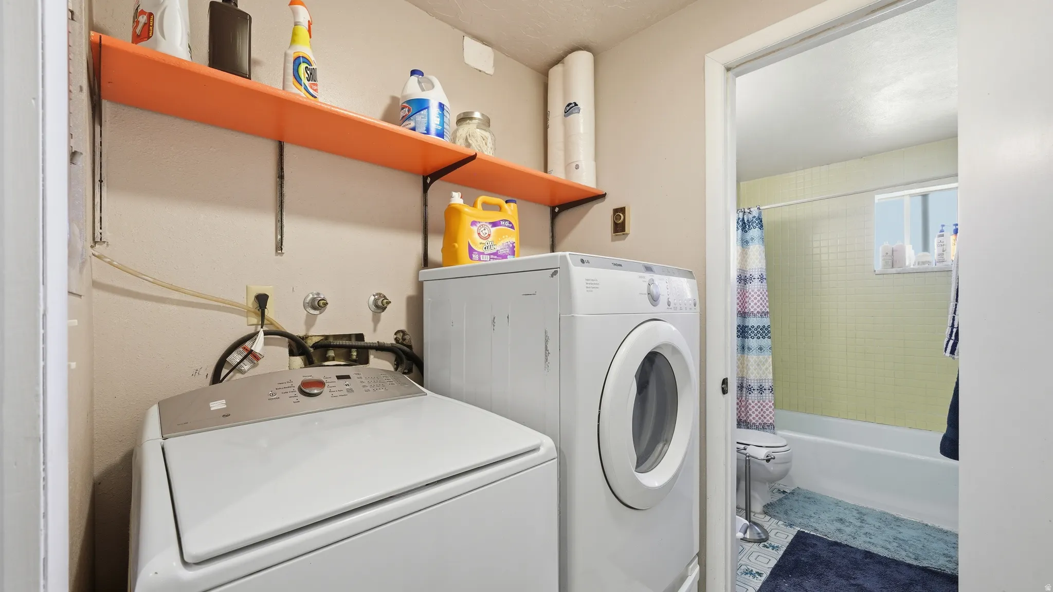 Dedicated laundry area featuring overhead shelving and connections for a washer and dryer