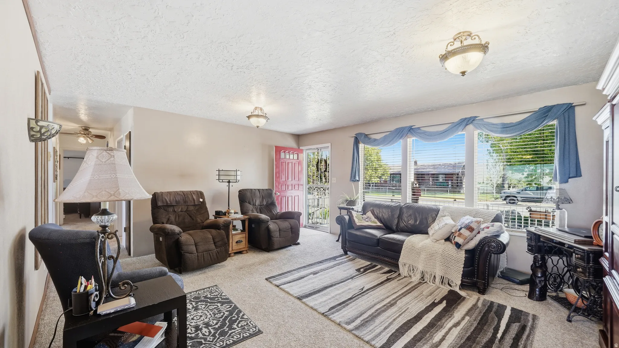 Spacious living area featuring neutral carpeting, a large picture window, and a pink paneled front door