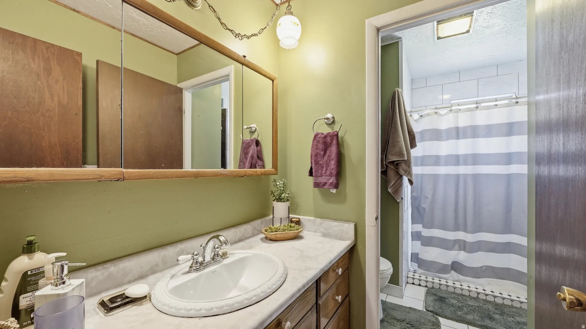 Bathroom vanity featuring a single sink with a chrome faucet, a stone-finish countertop, and wood-finish cabinetry