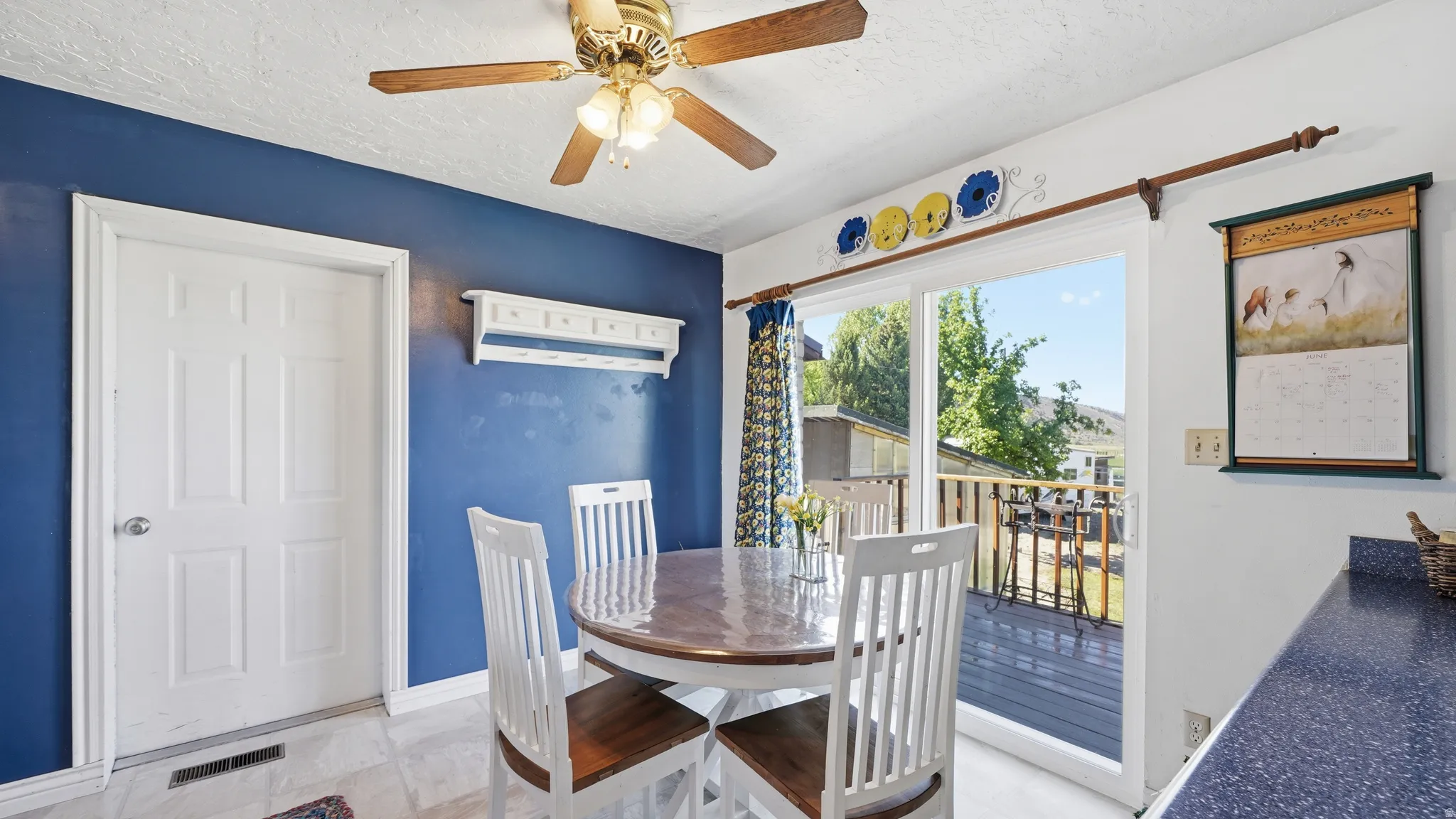 Dining area featuring a sliding glass door with external deck access, a ceiling fan with integrated lighting, and tile flooring