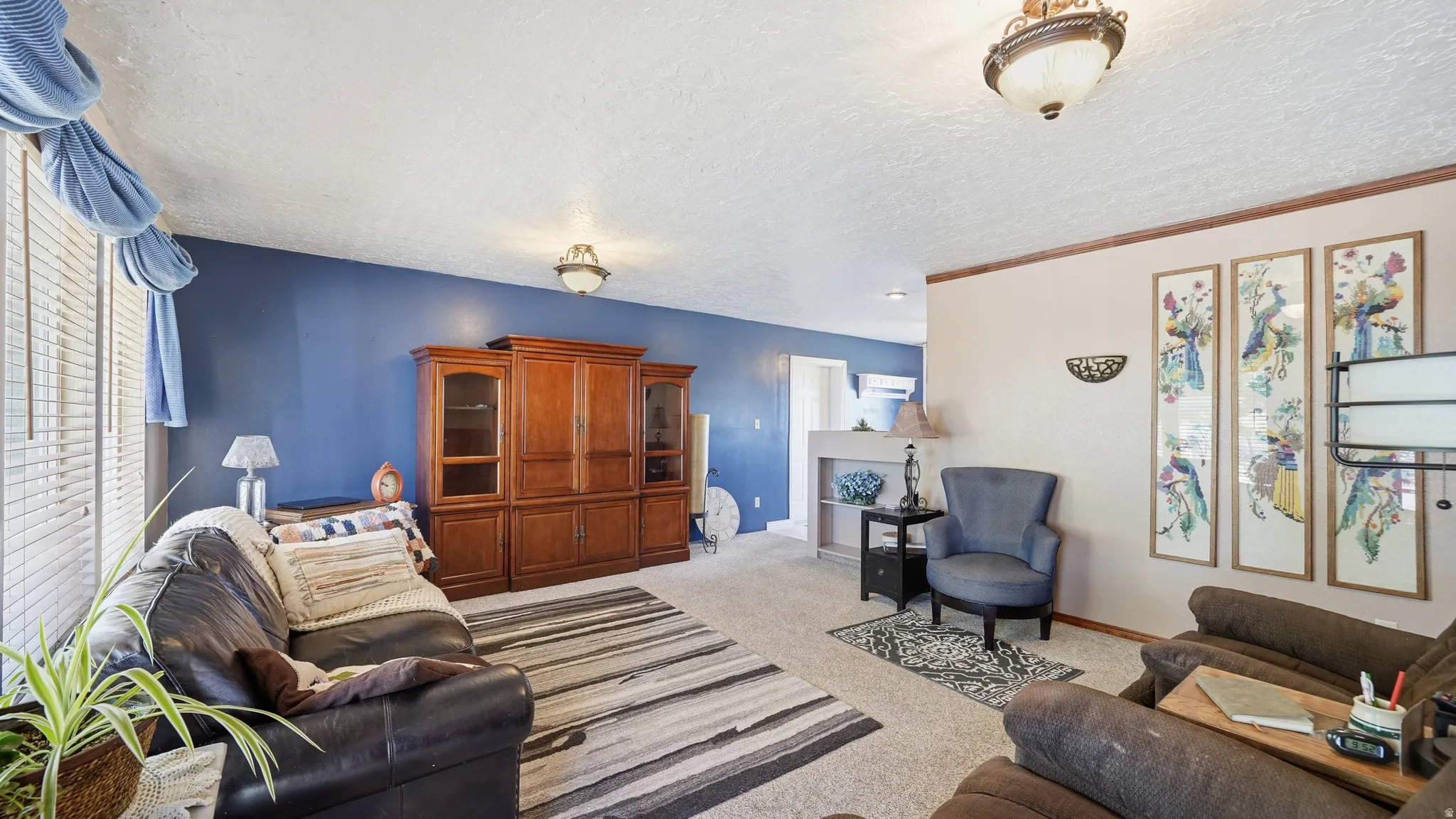 Spacious living area featuring neutral carpeting and a textured ceiling
