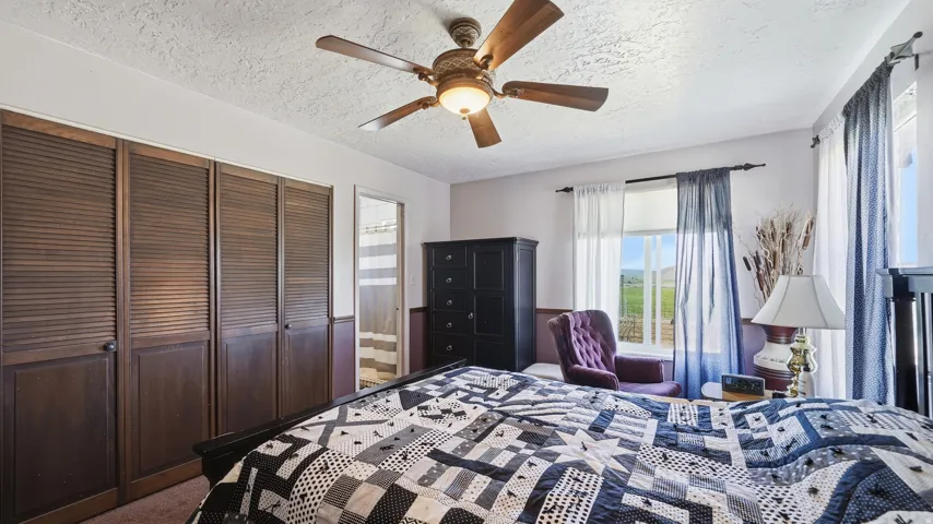 Room featuring louvered bi-fold closet doors, ceiling fan, and multiple windows with outdoor scenery