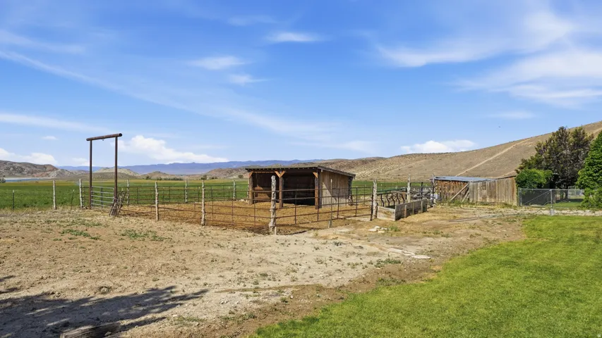 Expansive property featuring a rustic shelter, fenced enclosures, and a large metal gate