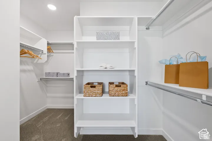 Custom closet organization system featuring white shelving, multiple hanging rods, and recessed lighting