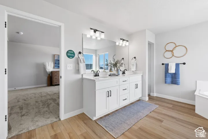 Bathroom featuring a double vanity with white cabinetry, dark hardware, and a light-toned countertop